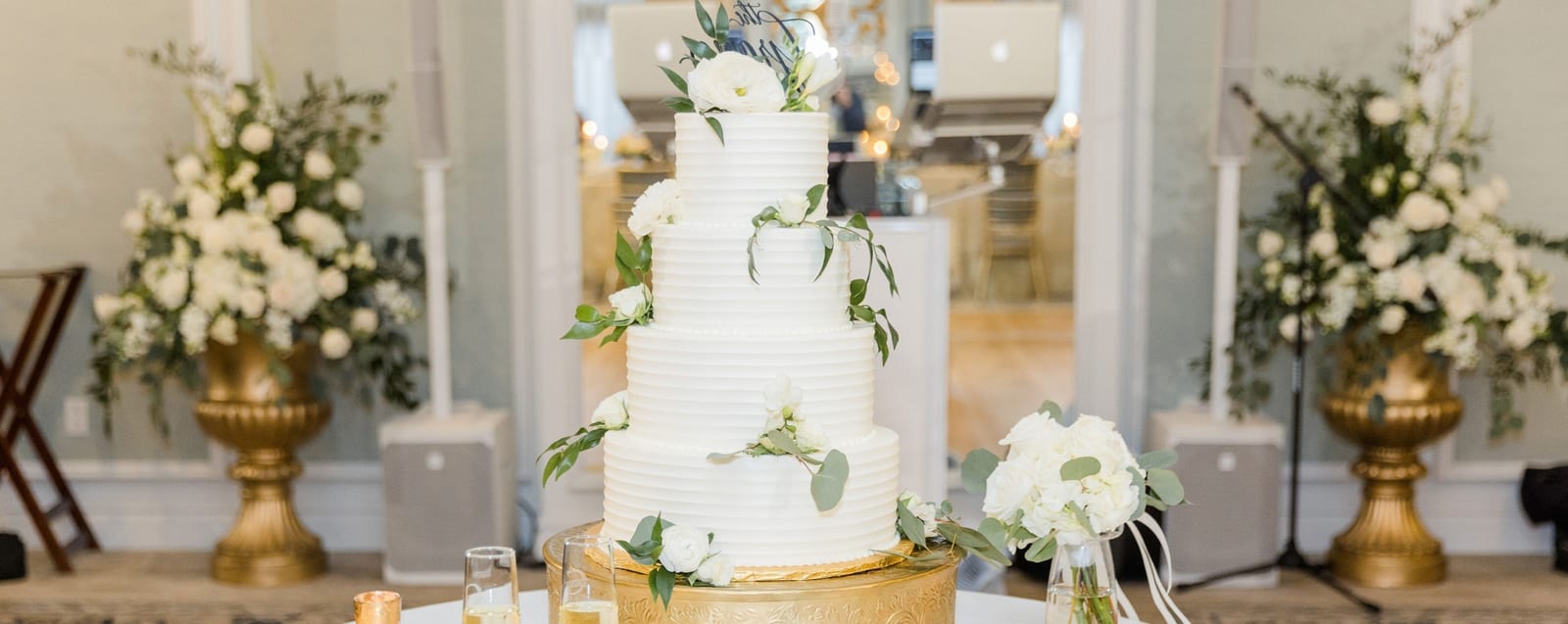 A five-tier white buttercream wedding cake with ranunculus and eucalyptus by Sweet Escape Cake Company in Indianapolis.