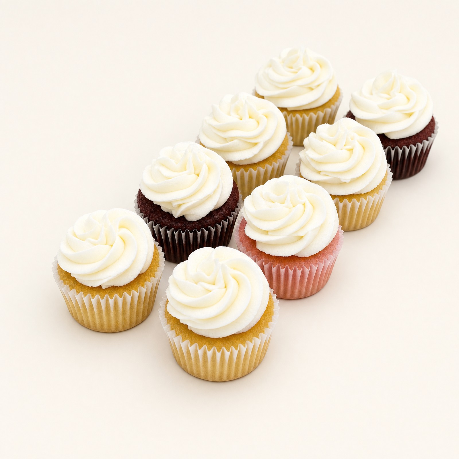 Assorted cupcakes in vanilla, chocolate, red velvet, and strawberry under matching white buttercream swirls, showing the range of the Sweet Escape Cake Company cake flavors list.