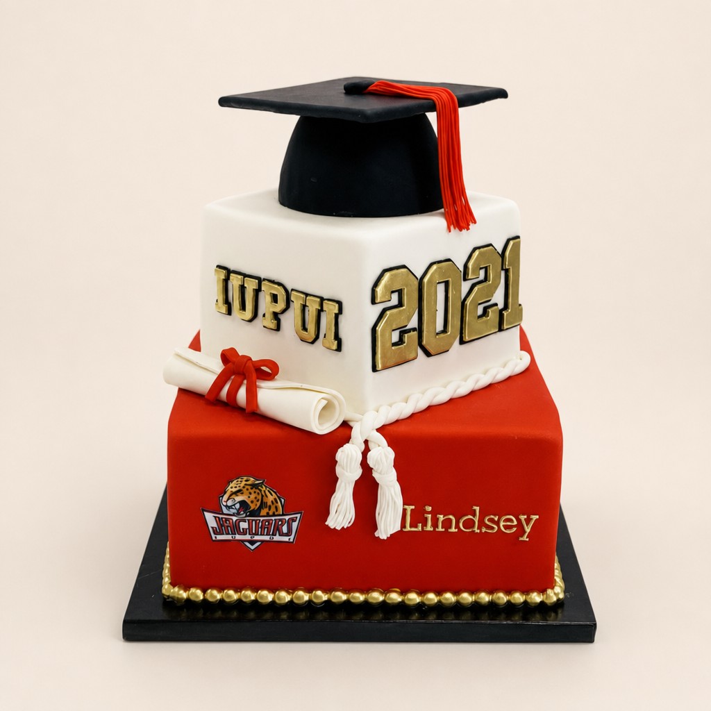 A red and white square two-tier IUPUI college graduation cake with a fondant graduation cap, tassel, and diploma from an Indianapolis cake shop.