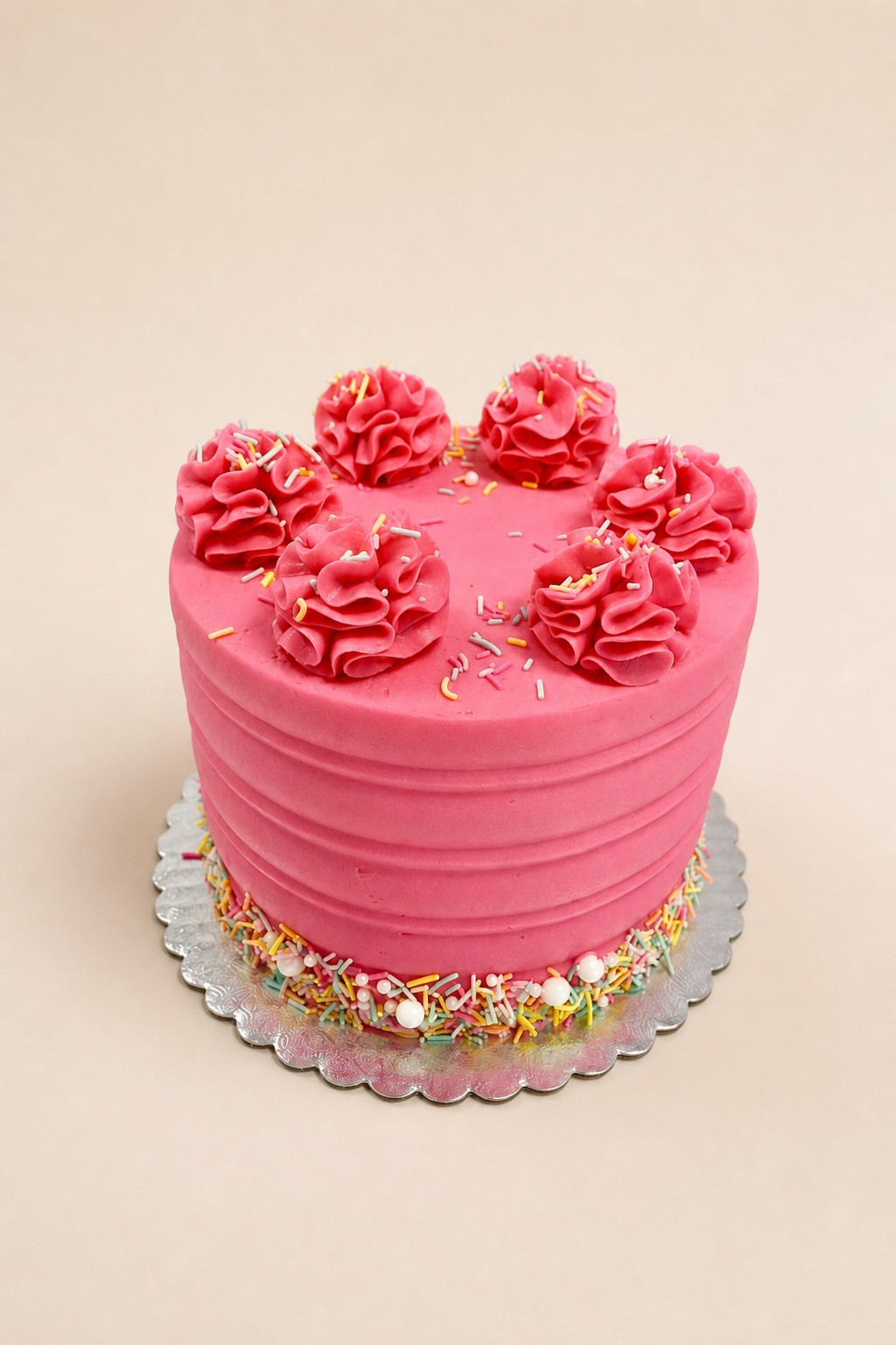 A vibrant pink single-tier round buttercream cake featuring horizontal ridged texture on the sides, topped with piped pink buttercream swirl