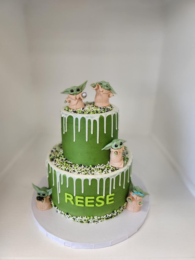 A two-tiered green Grogu (Baby Yoda) themed birthday cake featuring white drip icing, sprinkles, and edible 'REESE' lettering for a celebrat