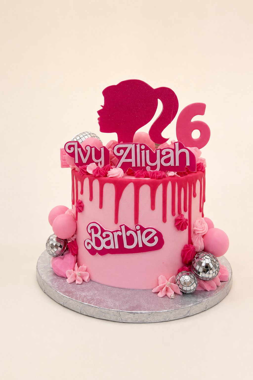 A vibrant pink Barbie-themed drip cake for a 26th birthday, featuring disco balls, pink balloons, and a personalized 'Ivy Aliyah' topper.