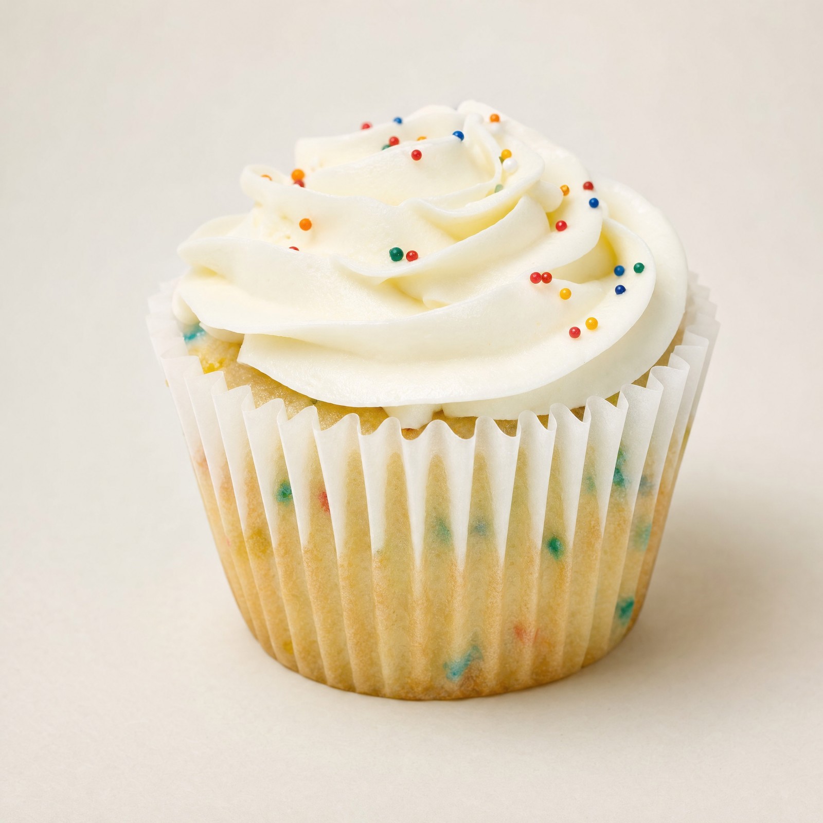 Two classic funfetti cupcakes with fluffy white buttercream frosting and colorful sprinkles, presented on a shiny gold cake stand.