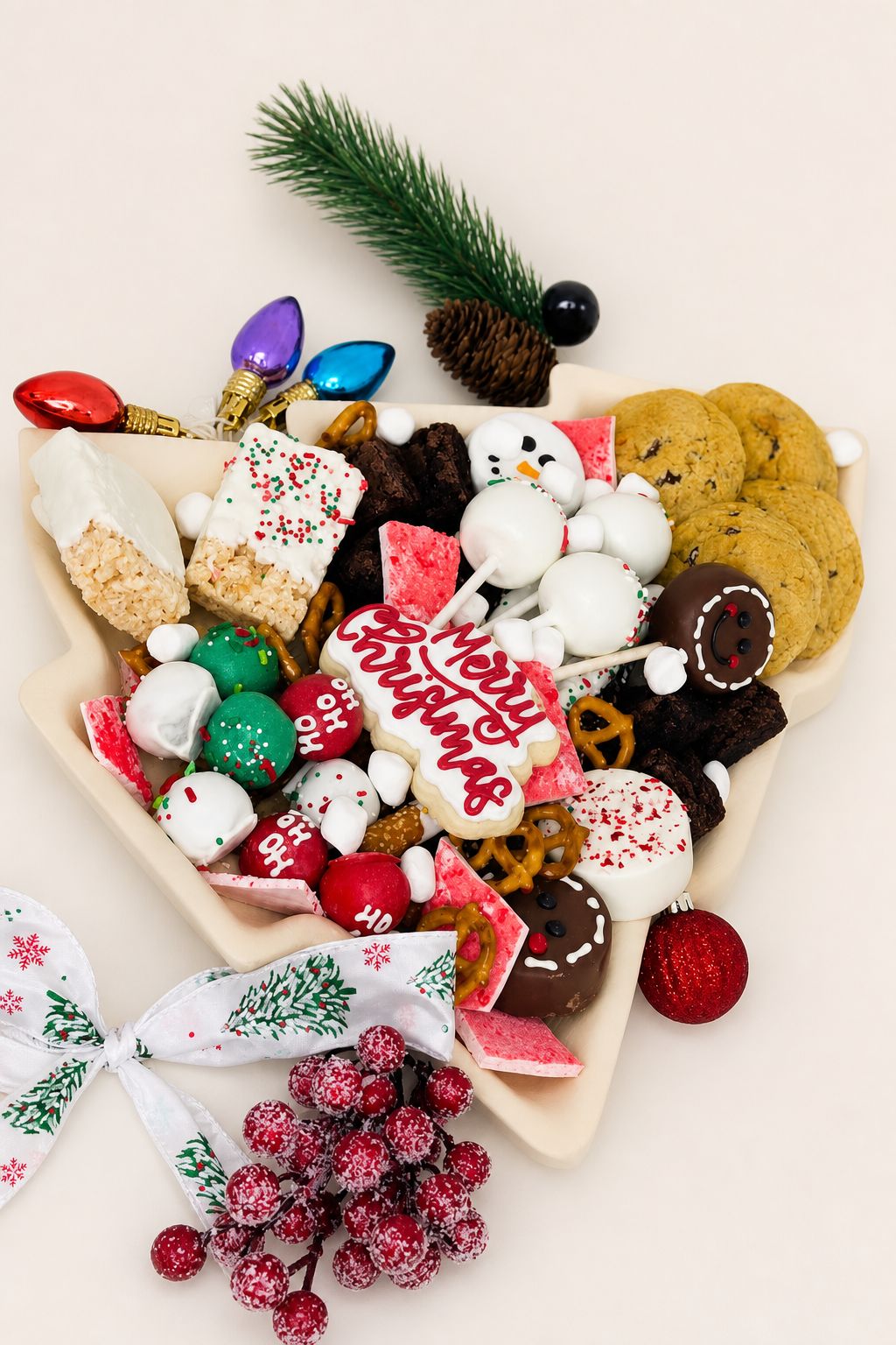 A festive Christmas dessert platter filled with an assortment of holiday treats, including decorated cookies, cake pops, chocolate-dipped it