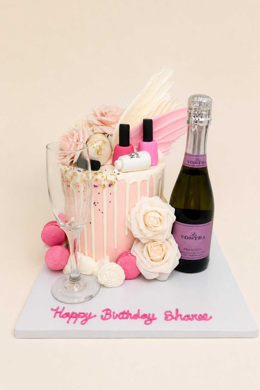 A elegant single-tier pink and white drip birthday cake adorned with fondant roses, gold leaf, purple sprinkles, pink macarons, and miniatur
