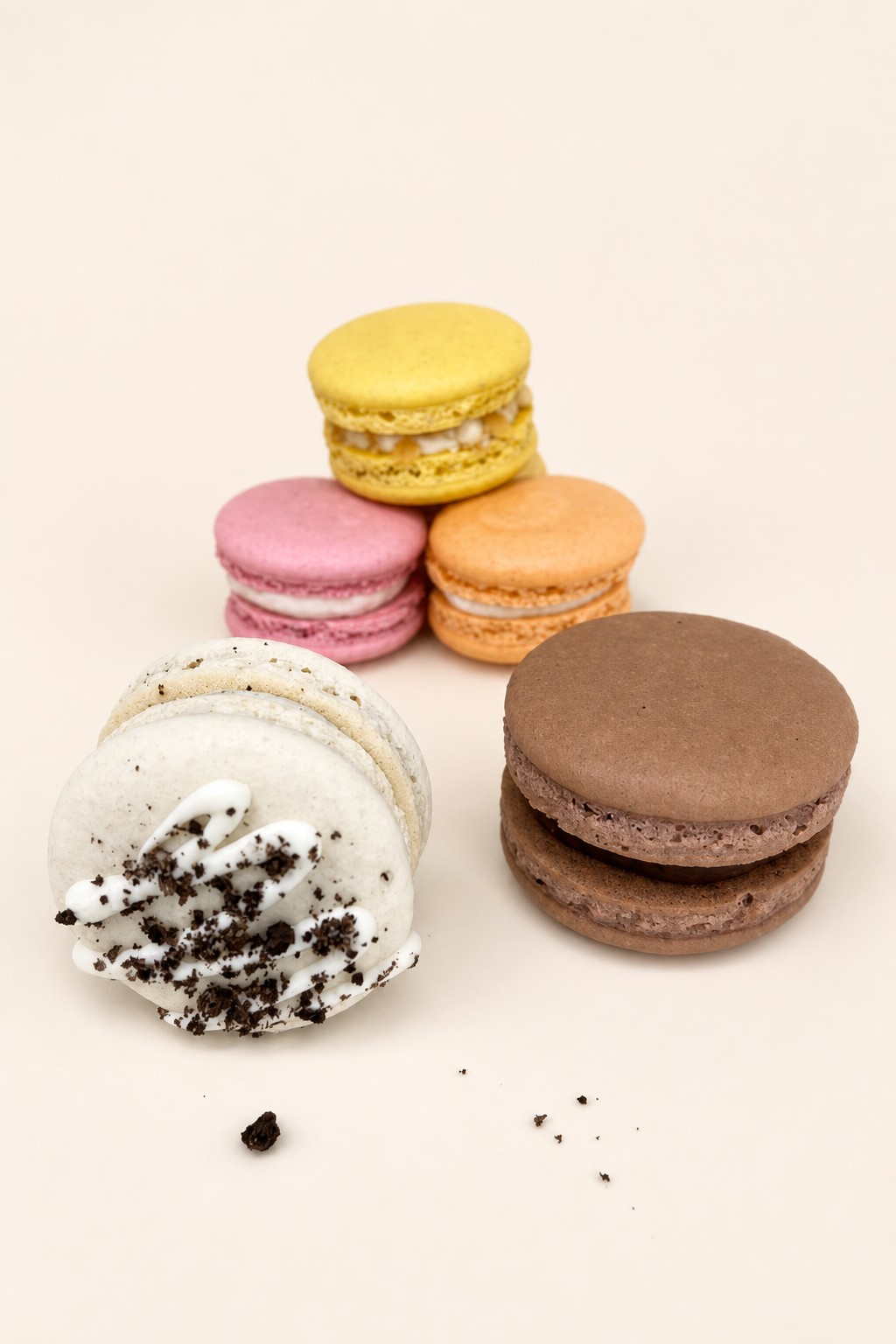 A vibrant assortment of macarons featuring yellow, pink, orange, white, and chocolate flavors, with one white macaron decorated with white d