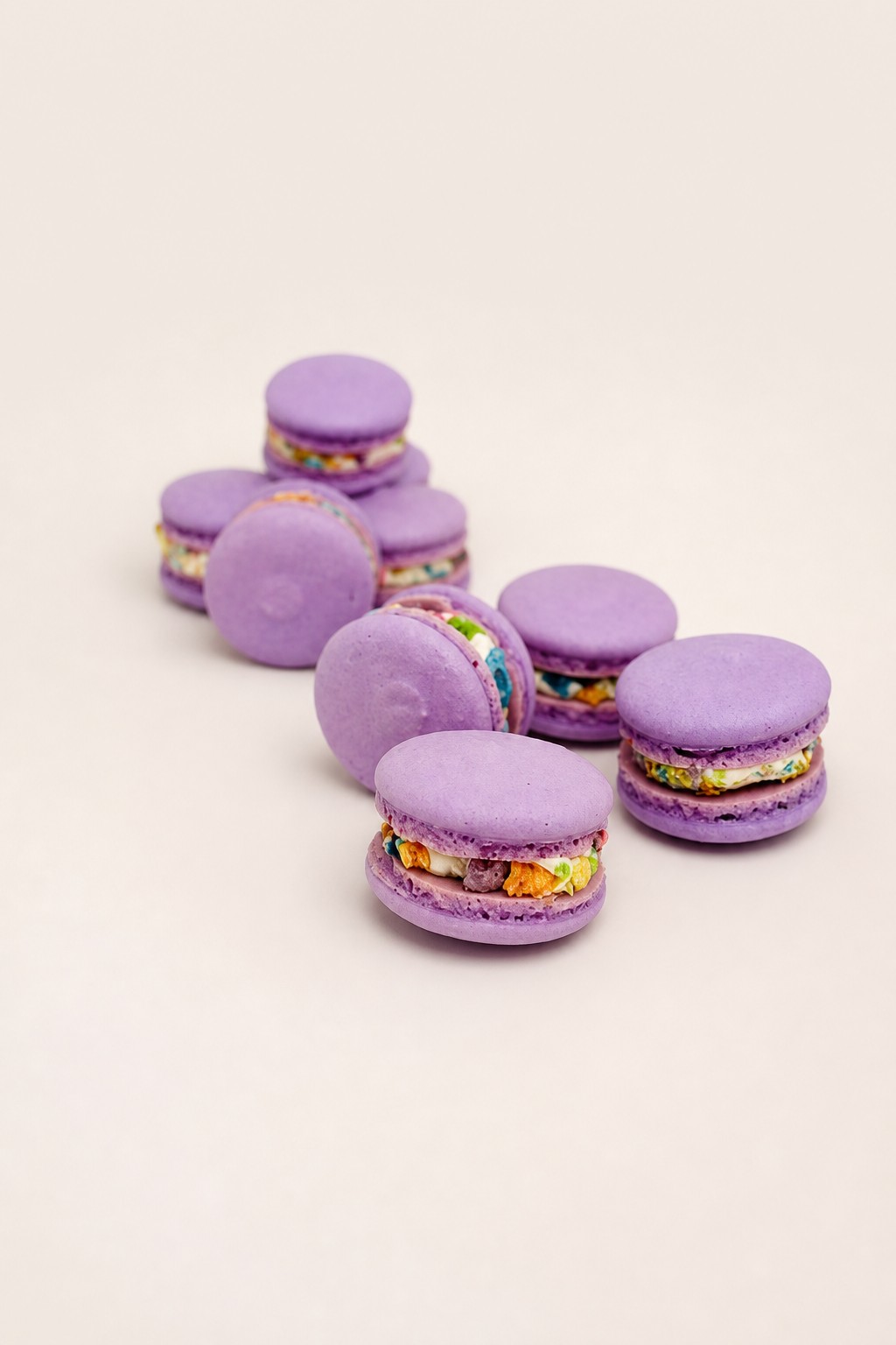 Purple macarons featuring a vibrant, multicolored cereal filling, elegantly displayed on a white rectangular plate.