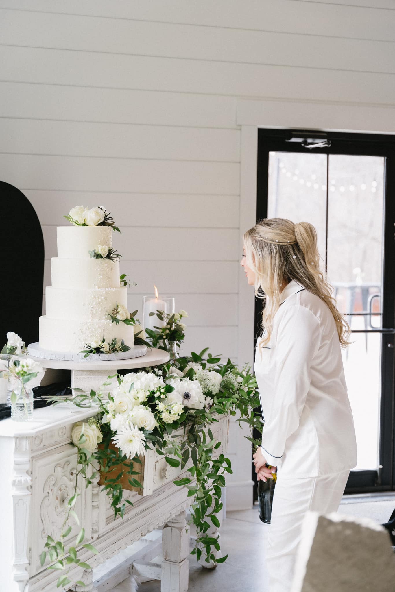 Four-tier white wedding cake with greenery