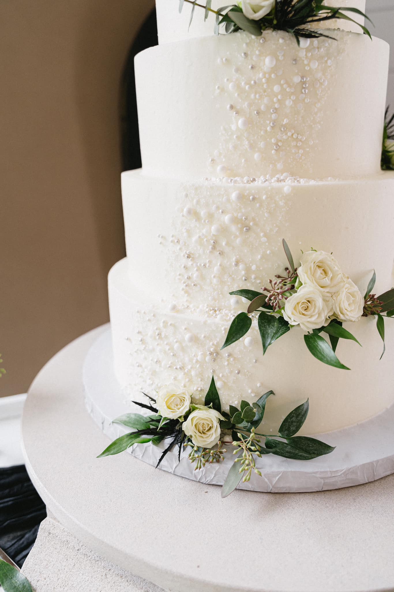 Four-tier white buttercream wedding cake with roses