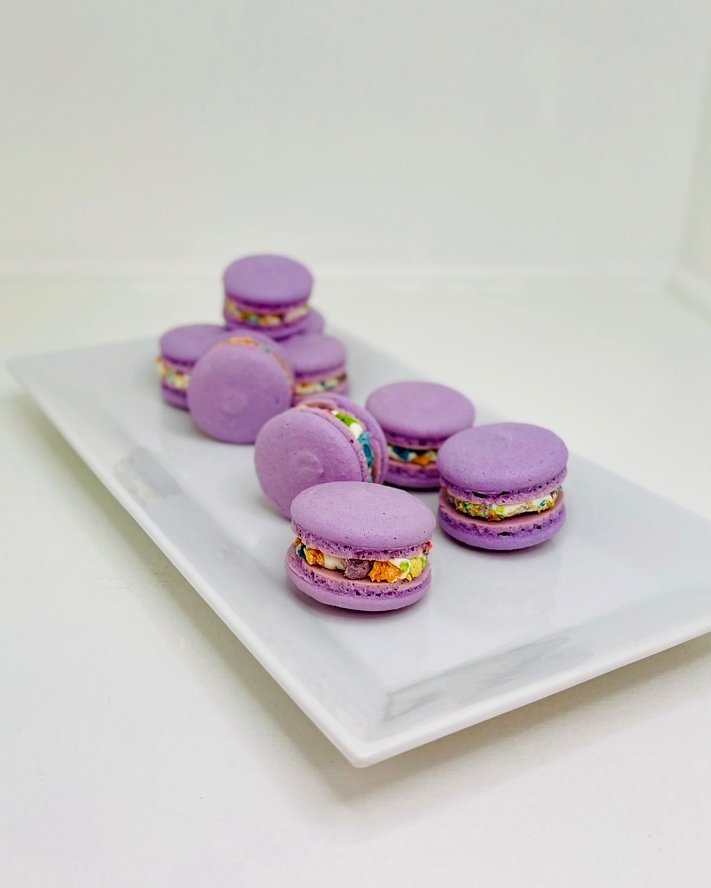 Purple French macarons with colorful confetti filling on a white plate